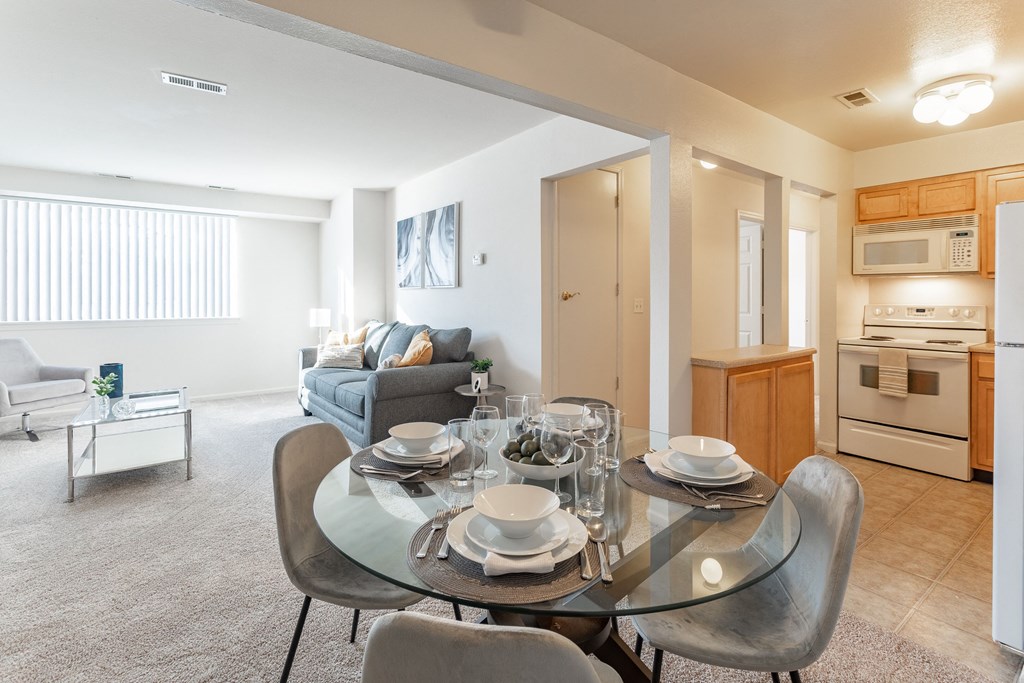 a living room with a glass dining table and a kitchen