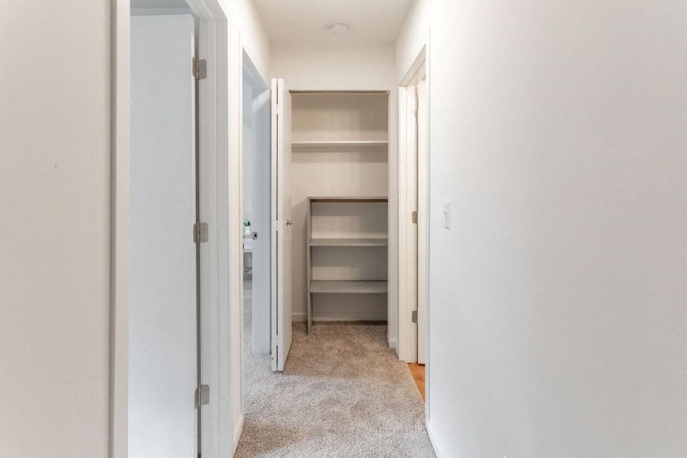 a room with a closet and a hallway with shelves in it