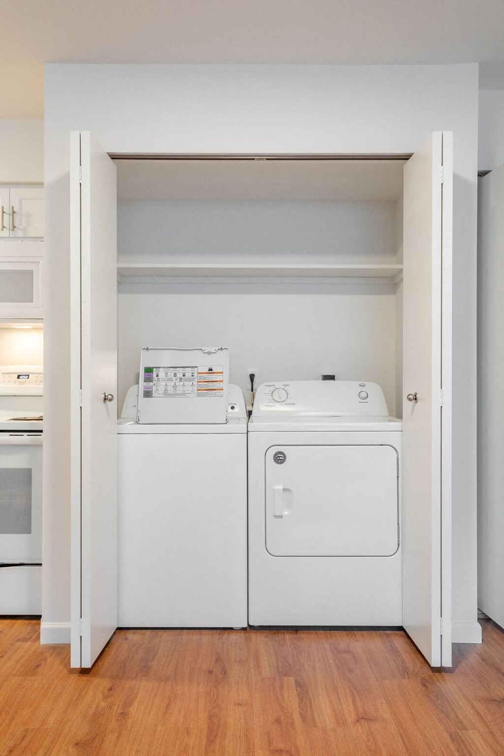 a washer and dryer in a closet with a wood floor