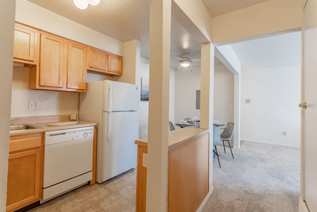 a kitchen with white appliances and wooden cabinets and a dining room with a white refrigerator