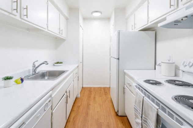 a kitchen with white cabinets and a sink and a refrigerator