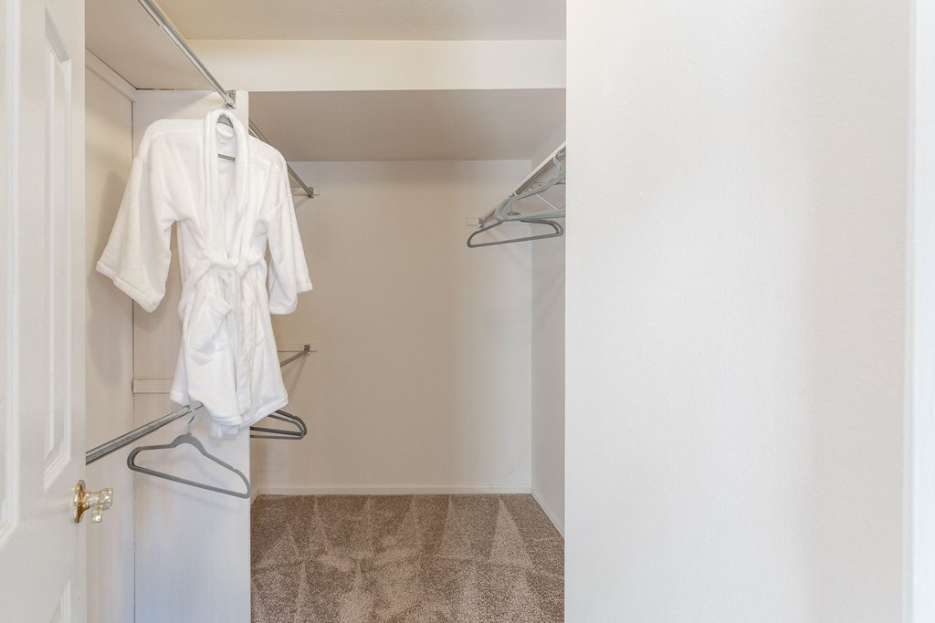 a walk in closet with a white robe hanging on a hanger in a bathroom