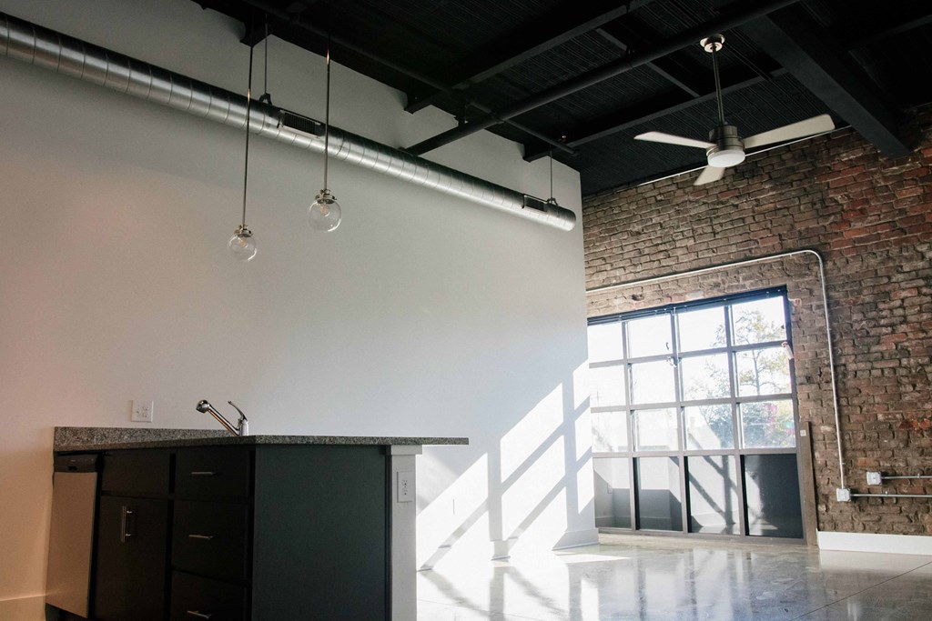 a kitchen in a loft with a brick wall and a large window