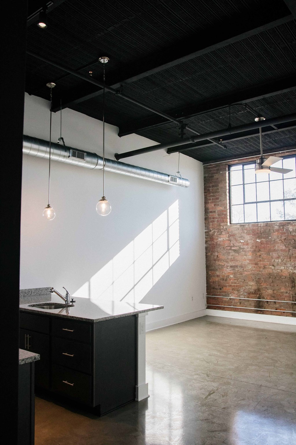 an empty room with two pendant lights and an exposed brick wall