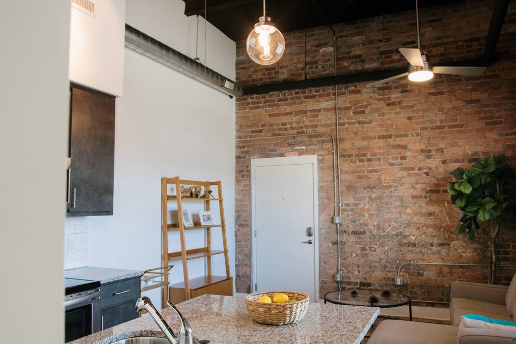 a kitchen and living room with a brick wall and a glass shower