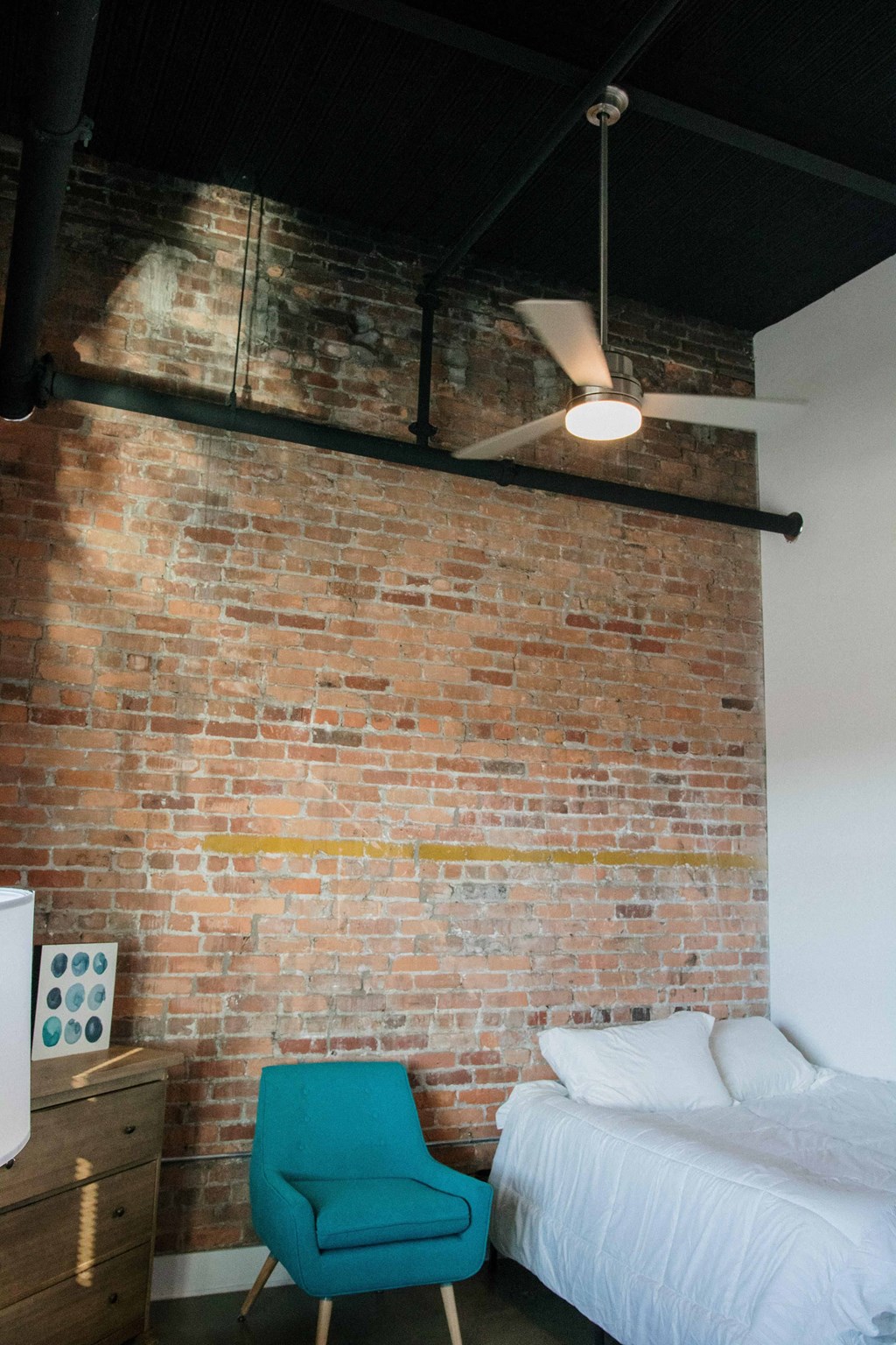 a bedroom with a brick wall and a bed and a blue chair