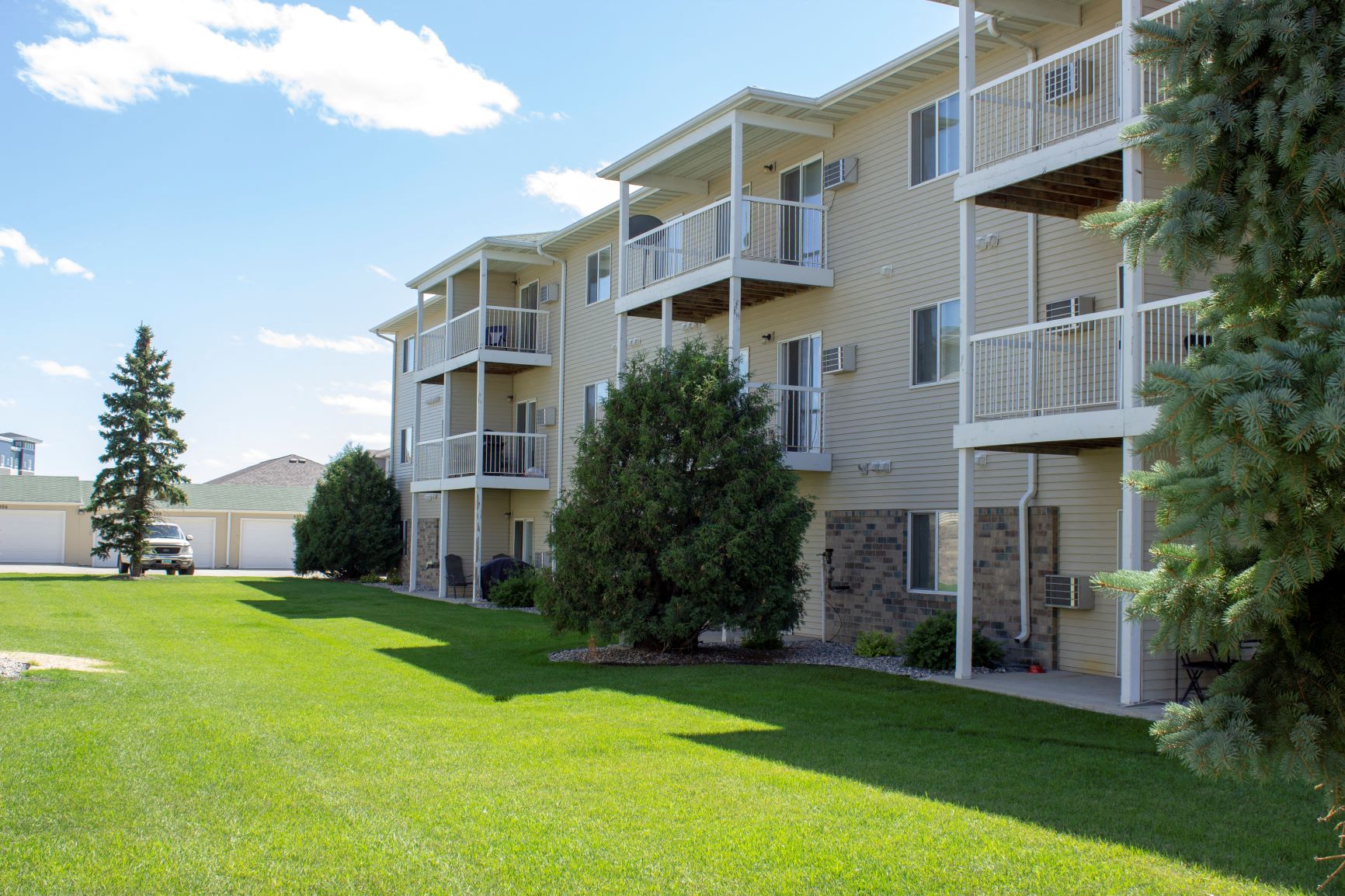 Exterior of Amber Valley in Fargo ND with green lawn, view of garages, and view of patios and decks