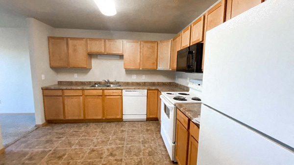Full kitchen at Amber Valley in Fargo ND with vinyl flooring, fridge, oven, microwave, sink, and garbage disposal