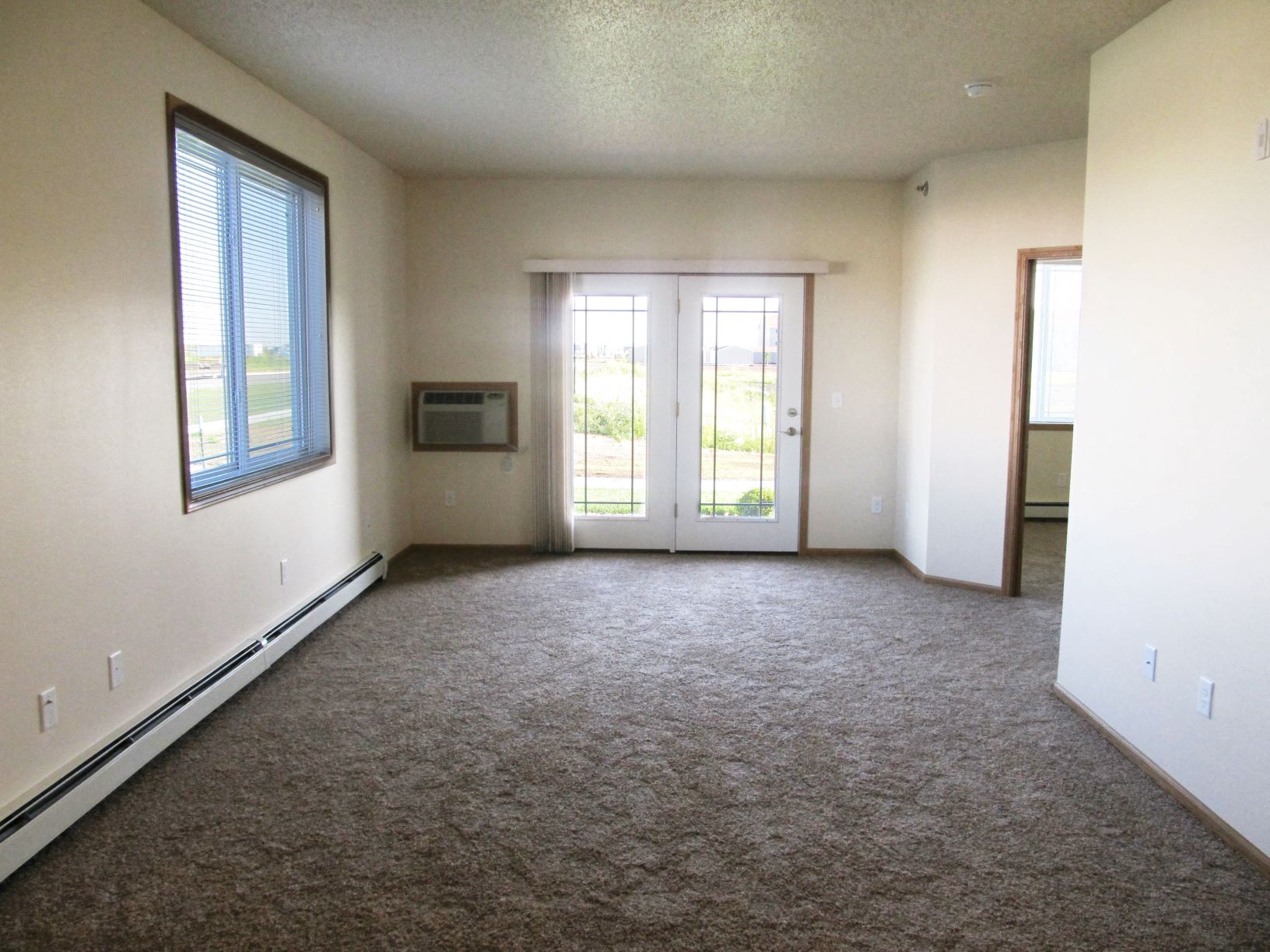 Living room with carpet and patio access in a one bedroom unit at Brandtplace apartment homes in Fargo, ND.