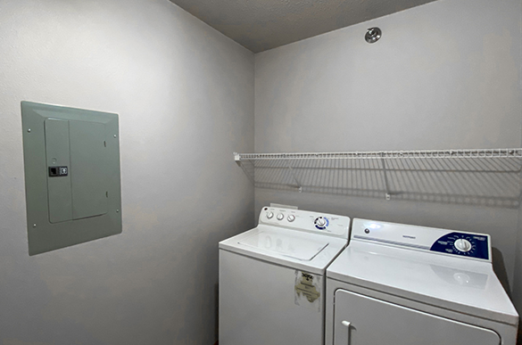 Convenient in-unit washer and dryer, fuse box, and shelves in a spacious laundry room at Osgood Townsite Apartments