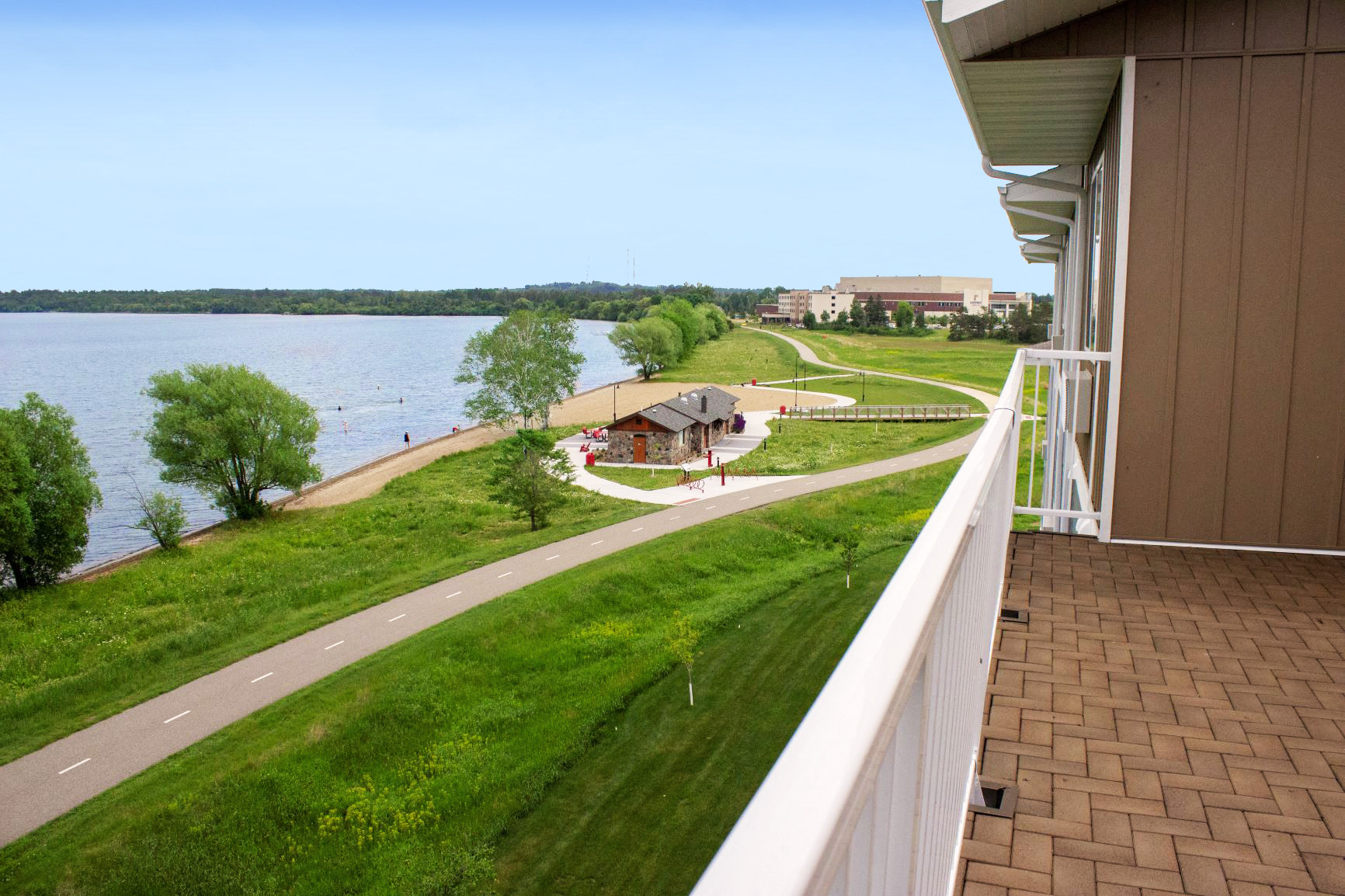 Bike path at South Beach apartments in Bemidji, Minnesota with a view of the lake, green lawn, and beach area.