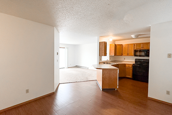 an empty living room and kitchen with wood flooring and