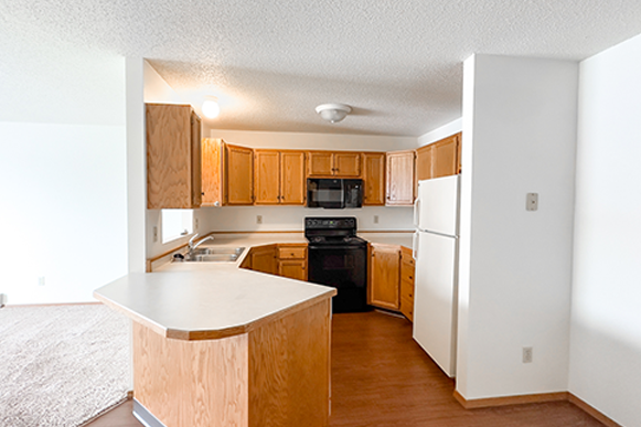 an empty kitchen with wooden cabinets and a white counter top