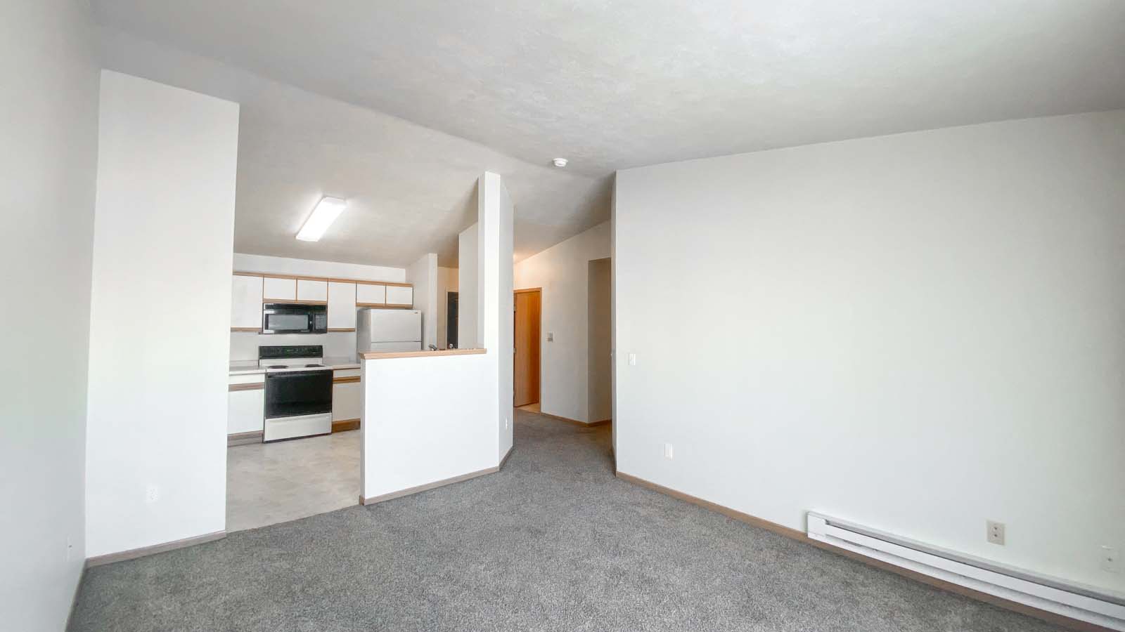 Open kitchen layout at Amber Crossing with heater, stove, and microwave and view of the front entrance