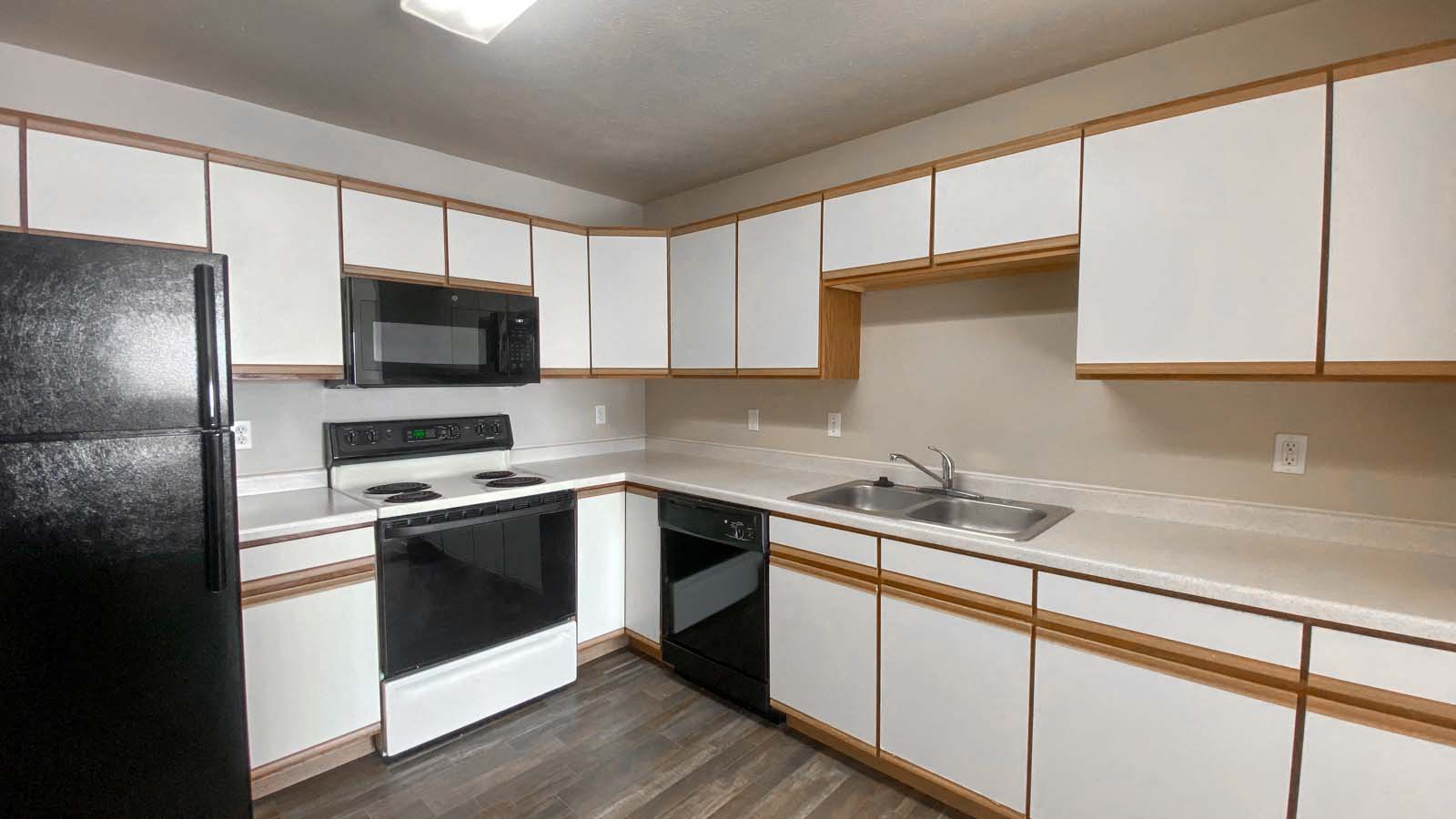 an empty kitchen with white cabinets and black appliances