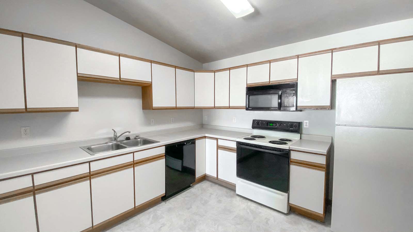 Full kitchen at Amber Fields with stove, microwave, sink, dish washer, and white vinyl flooring
