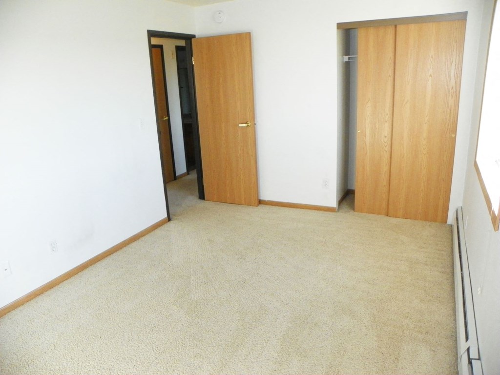 an empty room with two doors and a carpeted floor