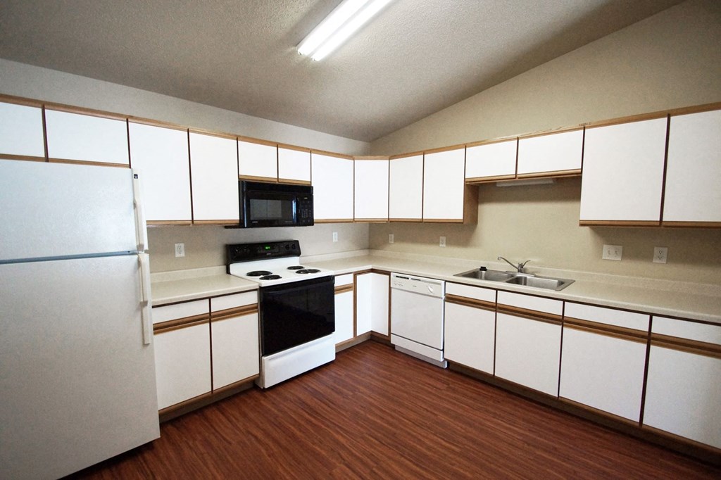 an empty kitchen with white cabinets and a black stove