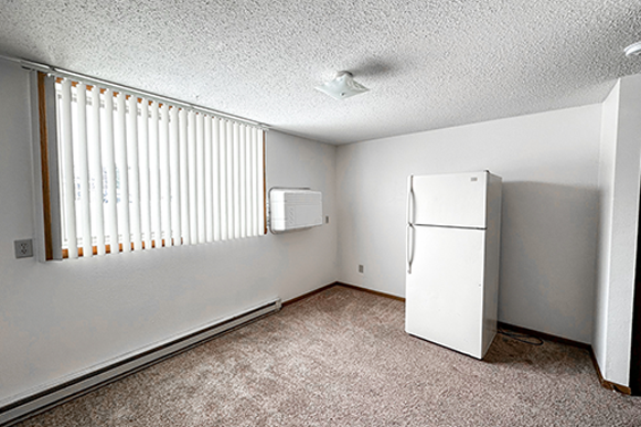 an empty room with a refrigerator and a window