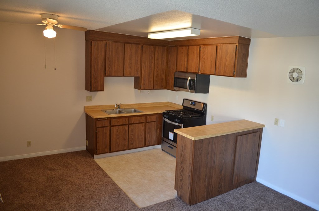 an empty kitchen with wooden cabinets and a stove and a sink