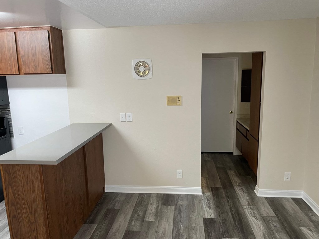 an empty kitchen with wooden floors and a door to a hallway