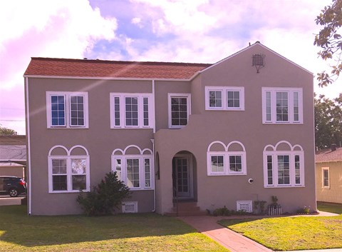 a pink house with white windows and a lawn