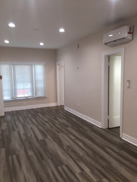 an empty living room with wooden floors and a window