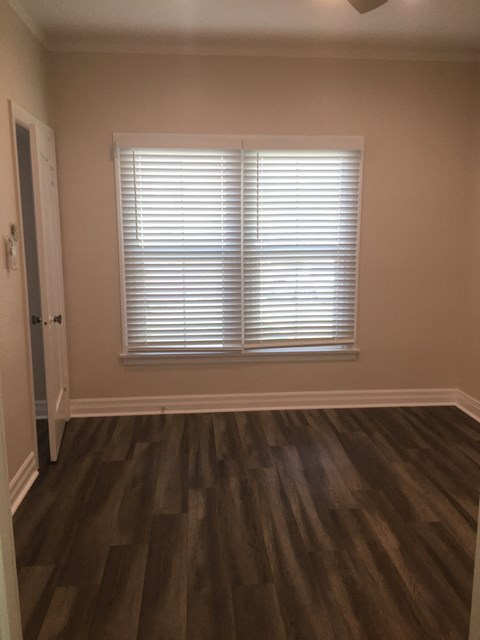 a living room with wooden floors and a window with blinds