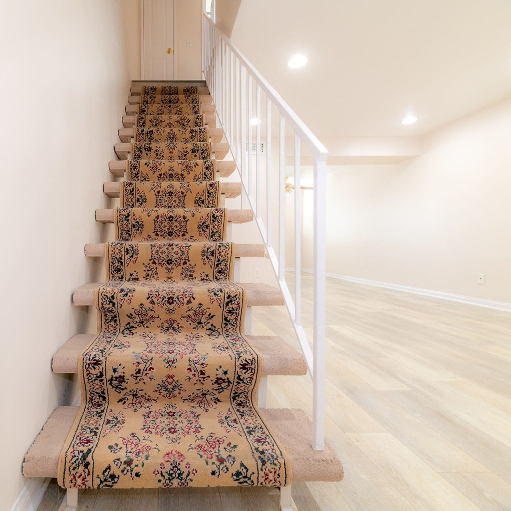 A staircase with a floral carpeted runner and white railings.