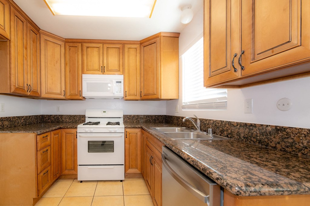 A kitchen with a white stove and wooden cabinets.