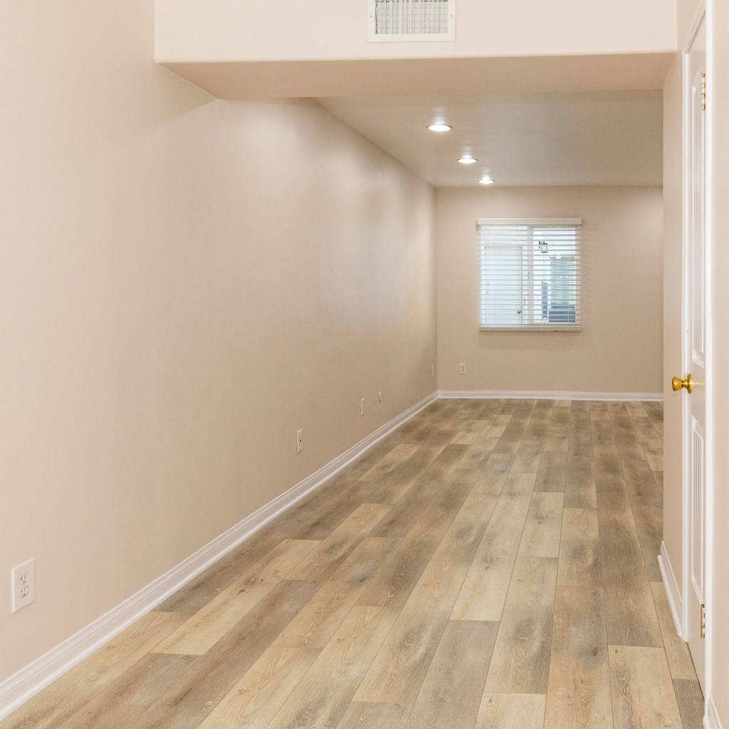 A room with wooden flooring and a window with blinds.