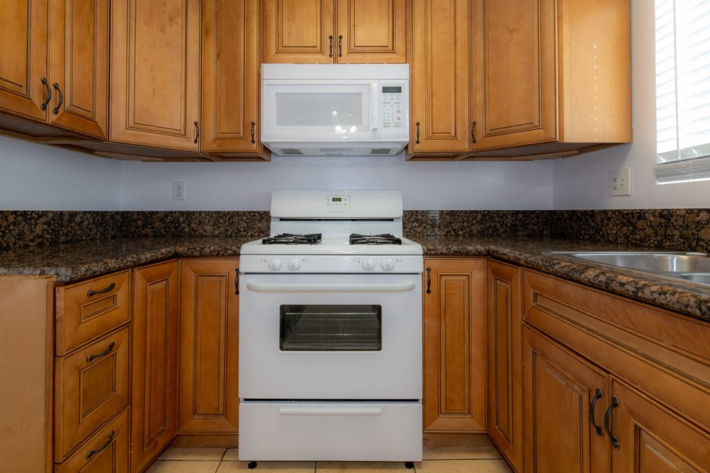 A white stove and oven in a kitchen with wooden cabinets.
