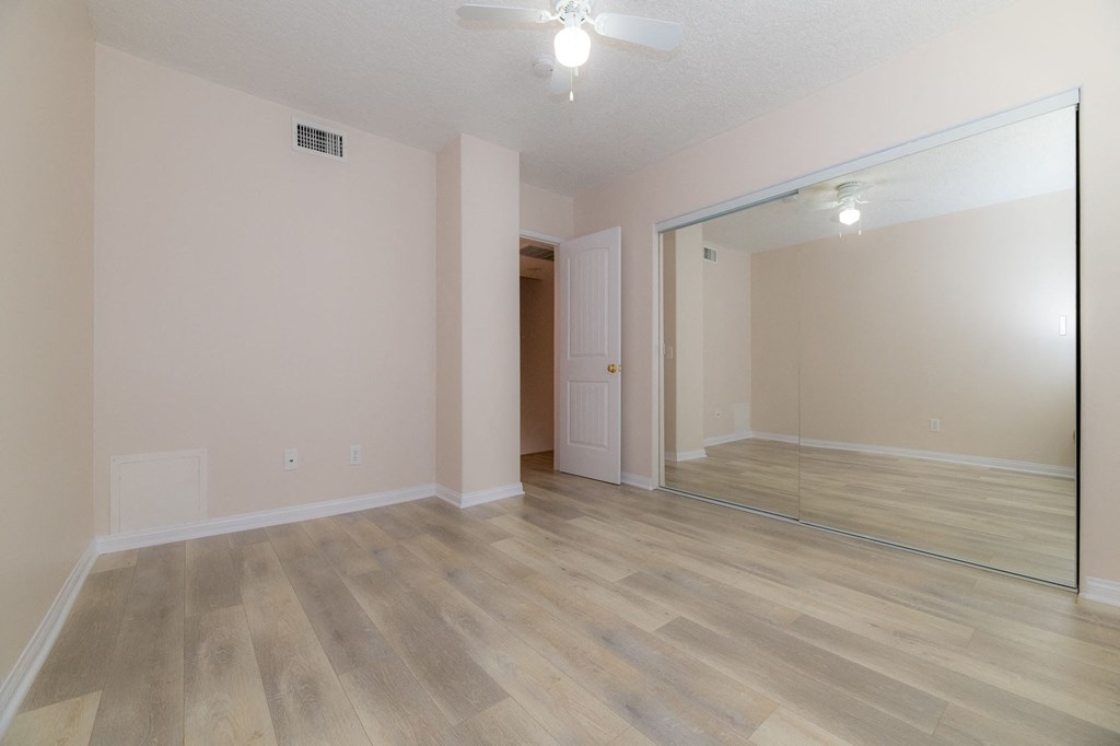 A room with a wooden floor and a mirror on the wall.