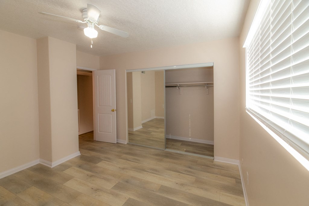 A room with a wooden floor and a white ceiling fan.