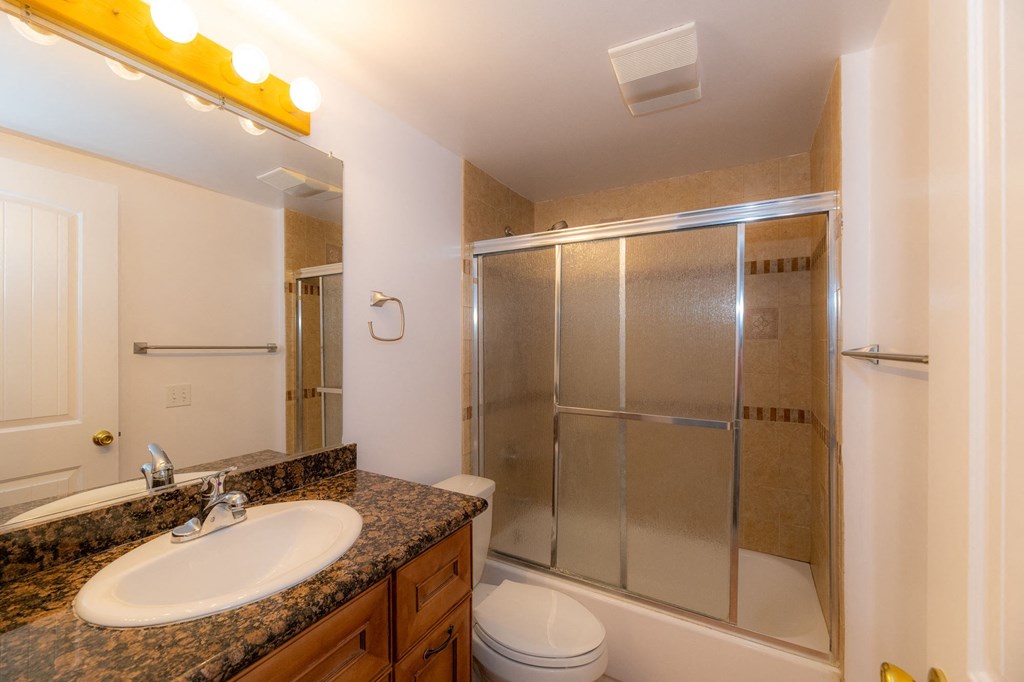 A bathroom with a sink, mirror, and shower.