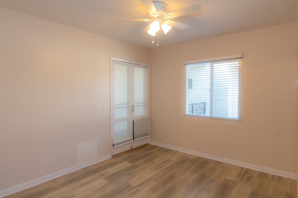 A room with a ceiling fan and a window with blinds.