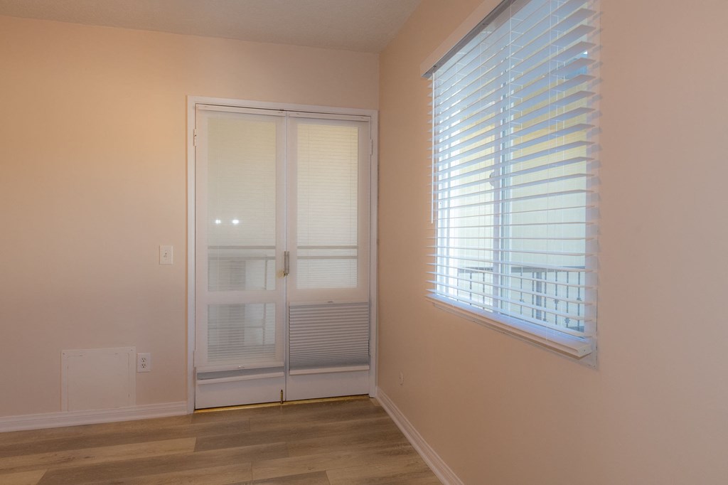 A room with a sliding glass door and a window with blinds.