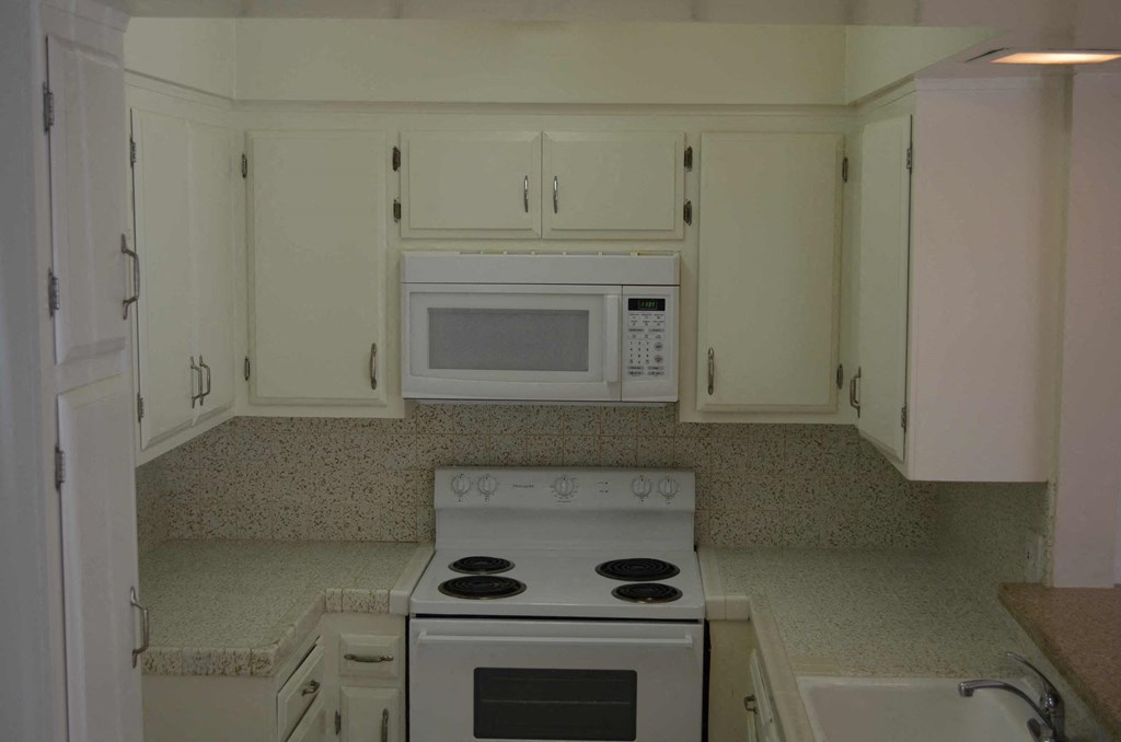 a kitchen with white cabinets and a stove and a microwave