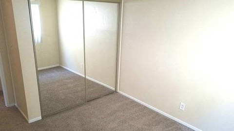 a room with a carpeted floor and a mirrored closet