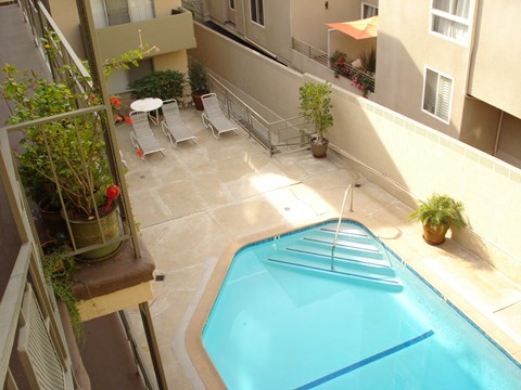 A small pool in a balcony surrounded by chairs and plants.