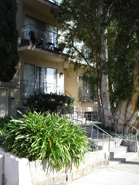 A building with a balcony and a tree in front.