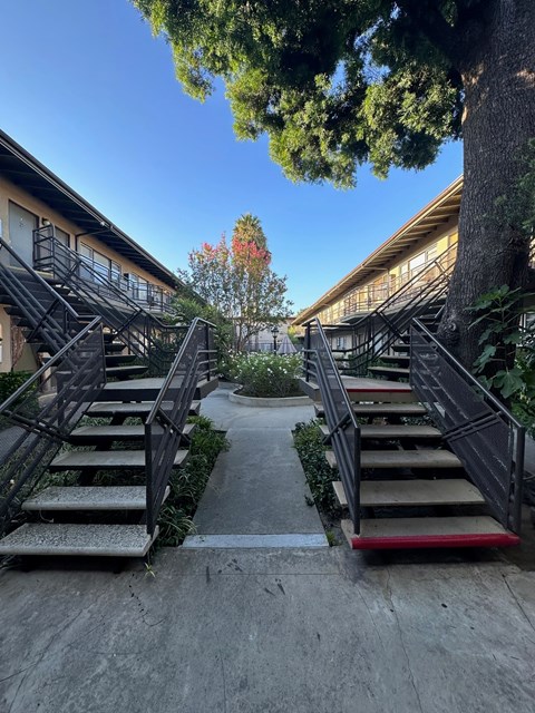 A set of stairs with a red handrail lead up to a building.