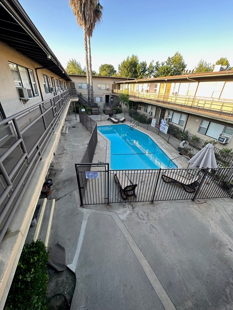 A pool surrounded by a fence and chairs.