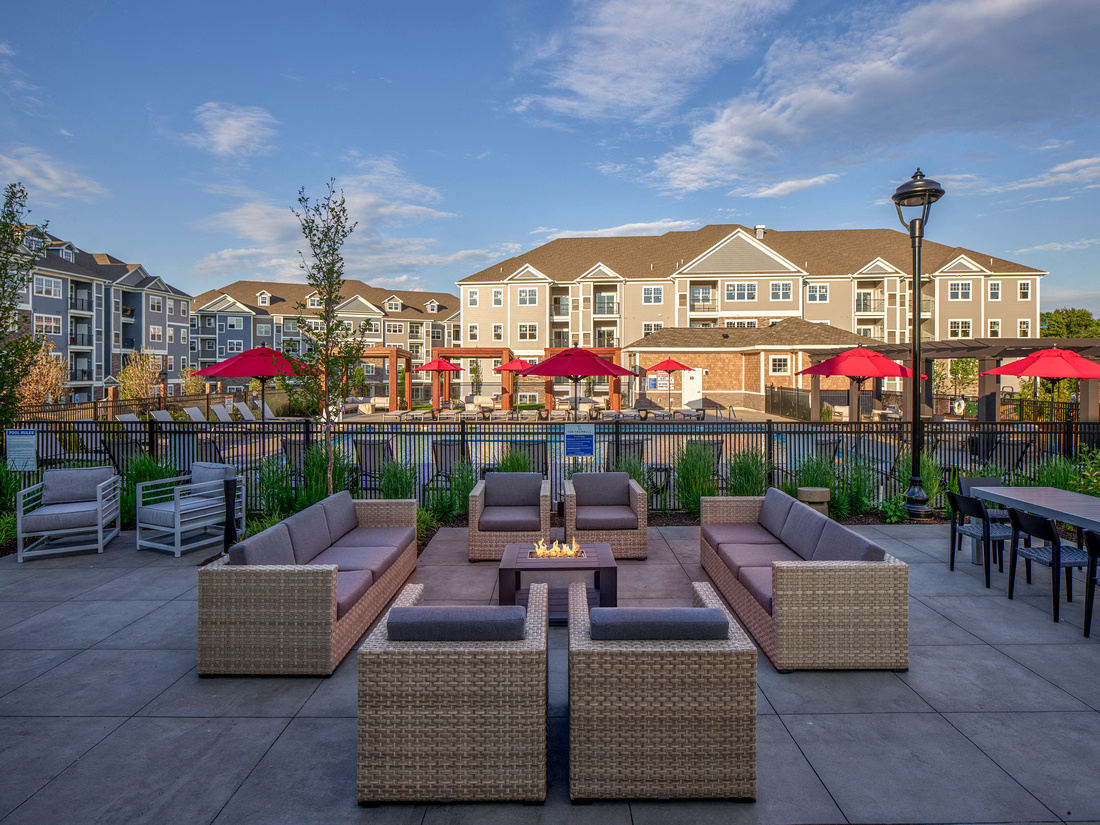 an outdoor patio with furniture and umbrellas in front of an apartment building