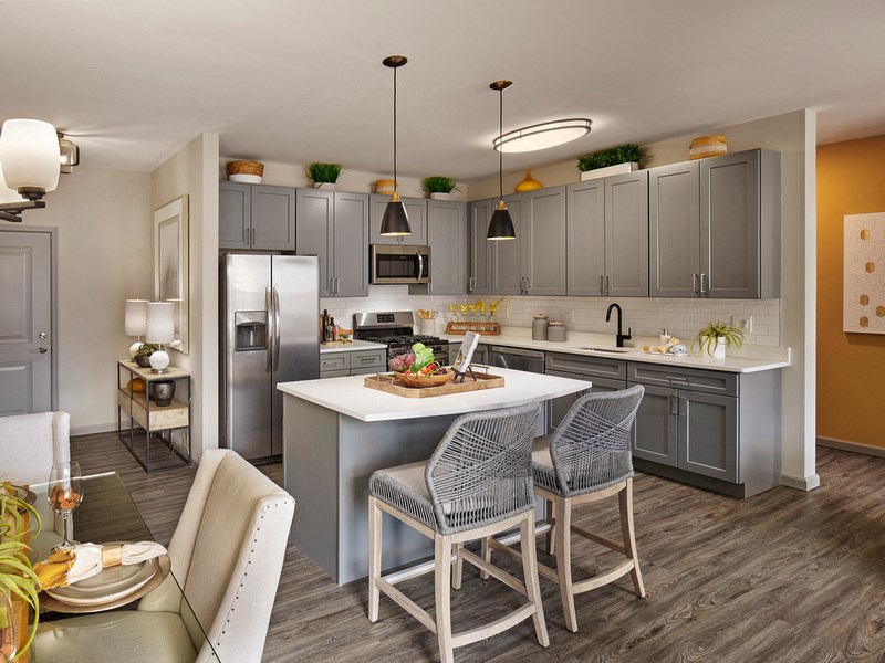 a kitchen with gray cabinets and a white island with chairs