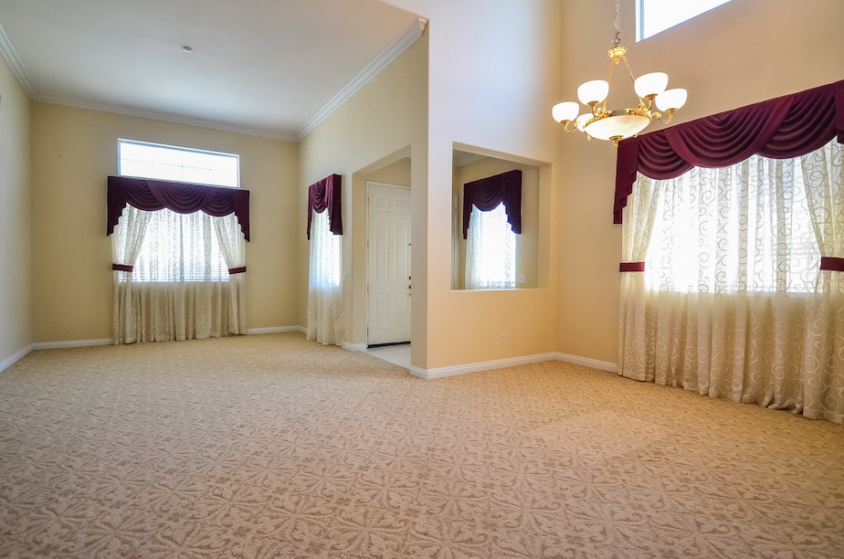 an empty living room with curtains and a chandelier