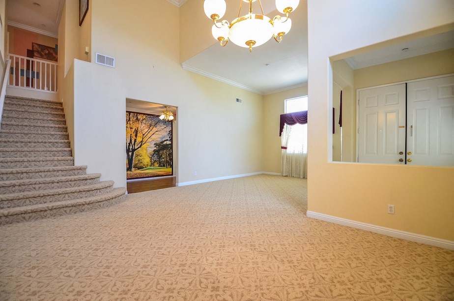 an empty living room with a staircase and a chandelier