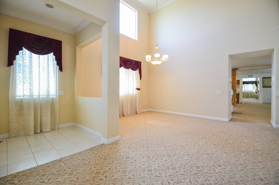 an empty living room with a large window and a carpet
