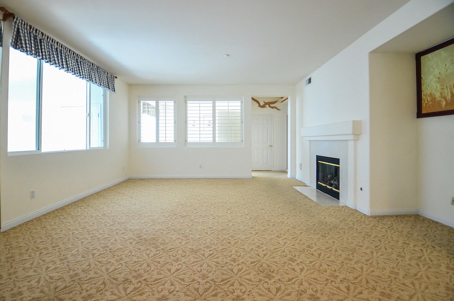 an empty living room with a fireplace and a carpet