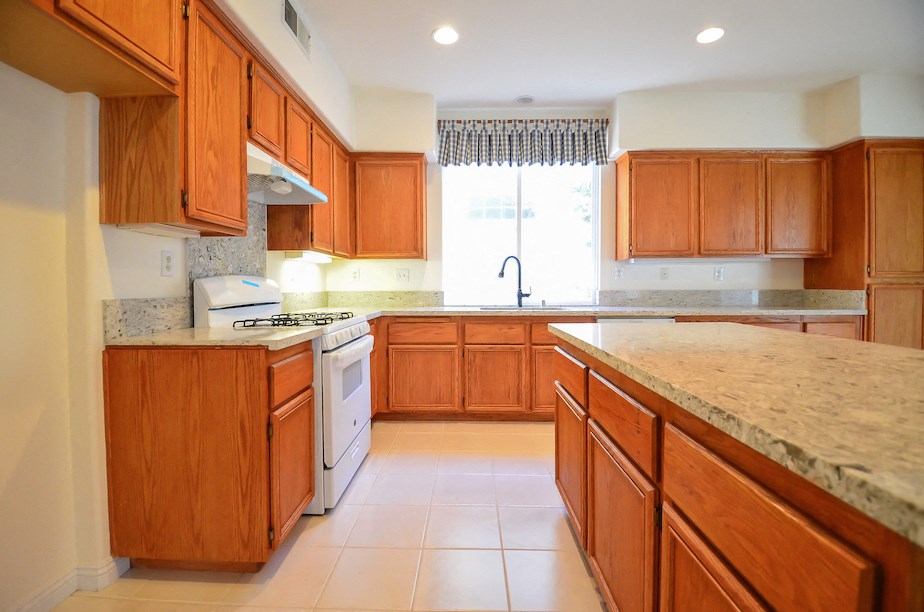 a kitchen with wooden cabinets and marble counter tops